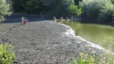 Dried out water with people stuck in the dry mud, while people pulling out fish nets from the water
