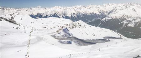 Landscape of alpine mountains in winter with solar farm on them